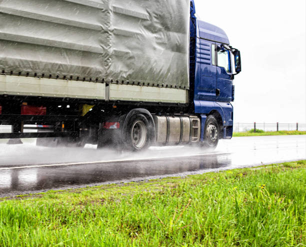 Semi-trailer semitrailer transports cargo on a wet road from rain in summer, close-up. Slippery road, trucking industry Semi-trailer semitrailer transports cargo on a wet road from rain in summer, close-up. Slippery road truck rain stock pictures, royalty-free photos & images