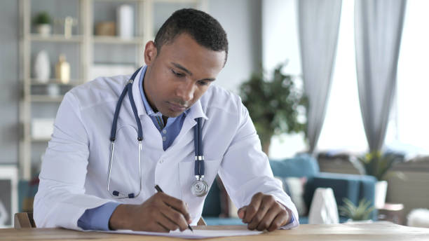 médecin afro-américain rédigeant un rapport médical de patient, paperasse - 16747 photos et images de collection