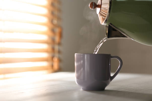 istock Pouring hot water into cup on white wooden table, space for text. Good morning 1338821909