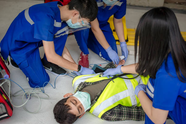 Emergency medical teams are helping unconscious patients by using automated external defibrillators (AED) and providing oxygen. During the rescue of unconscious workers at the construction site Emergency medical teams are helping unconscious patients by using automated external defibrillators (AED) and providing oxygen. During the rescue of unconscious workers at the construction site emergency response workplace stock pictures, royalty-free photos & images