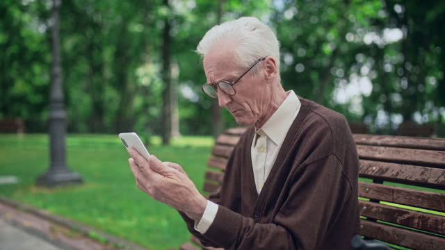 Mature man looking on smartphone display through eyeglasses, eyesight problems