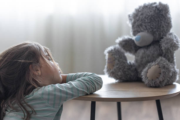 istock Sad little girl playing with a teddy bear. 1338829857