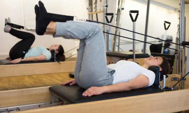 femme pilates stretching sport dans un lit réformateur - pilates machine photos et images de collection