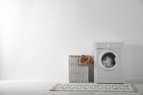 istock Modern washing machine and laundry basket near white wall indoors, space for text. Bathroom interior 1338830841