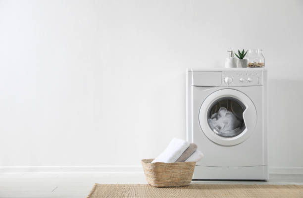 istock Modern washing machine and laundry basket near white wall indoors, space for text. Bathroom interior 1338831247
