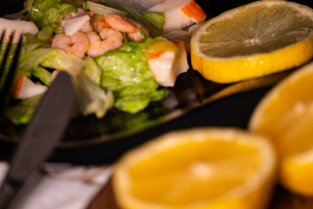 seafood salad composition with shrimps and surimi with cutlery and glass of white wine and lemons