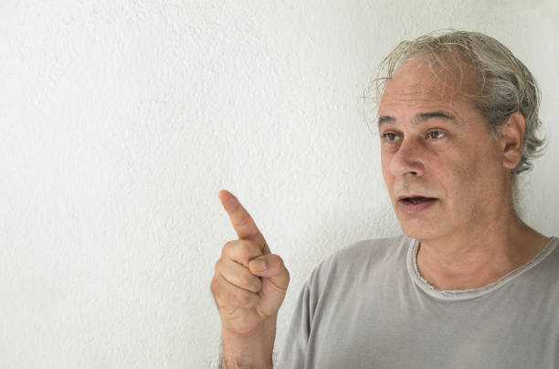 istock mature man pointing to the right on a white background 1338832140