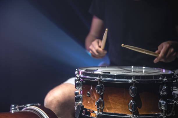 istock Drummer playing drum sticks on a snare drum on black background copy space. 1338833457