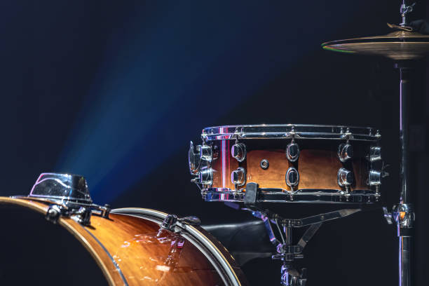 Part of a drum kit, drums on a dark background, copy space. Drum set in a dark room with beautiful lighting, snare drum, cymbals, bass drum. drum container stock pictures, royalty-free photos & images