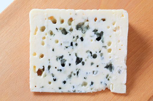 Wedge of blue cheese on a cutting board