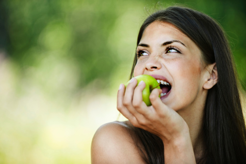 Young woman smiling and biting an apple