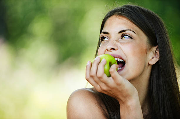 Young woman smiling and biting an apple stock photo
