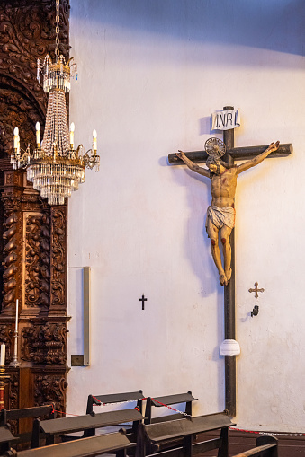 Large crucifix with a Covid-19 warning in Igrejo Matriz de Sao Sebastio build in 1547 is the main church in Ponta Delgada on the Azorean Island San Miguel. The style is originally gothic but in the 18th century it was modernized in a more baroque style.