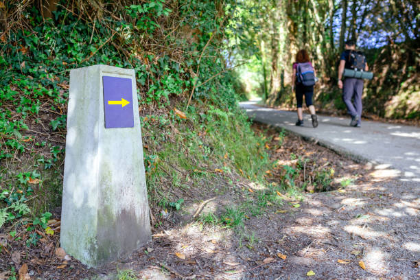 pietra miliare del cammino di santiago con pellegrini che camminano - st james way foto e immagini stock