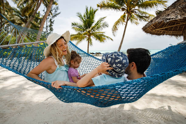 famiglia rilassata che si diverte sull'amaca sulla spiaggia. - hammock beach vacations tropical climate foto e immagini stock