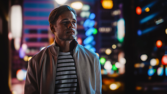 Handsome Blonde Man Standing on a Street of a Night City. Thoughtful Attractive Young Man Traveling, Looking Around Urban Center Contemplating Business Ideas, Future Career. Air of New Possibilities
