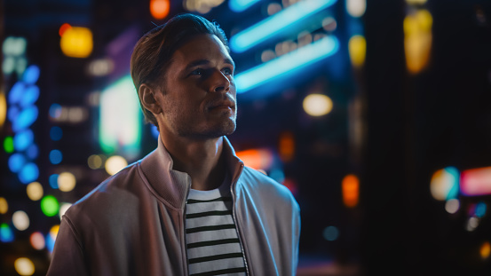 Handsome Blonde Man Standing on a Street of a Night City. Thoughtful Attractive Young Man Traveling, Looking Around Urban Center Contemplating Business Ideas, Future Career. Air of New Possibilities