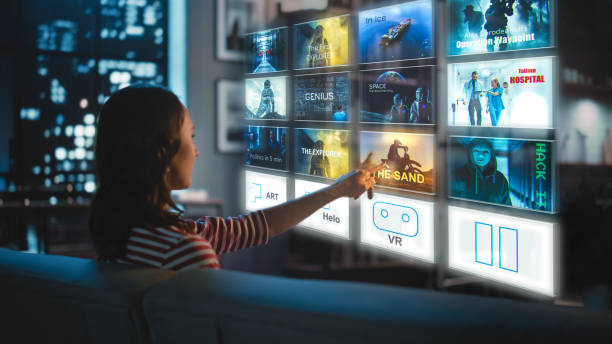 une belle jeune femme est assise sur un canapé la nuit à la maison et choisit un film à regarder sur un écran hologramme de réalité augmentée futuriste. concept futuriste. - downloading photos et images de collection