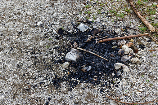 burnt charred fireplace on a gravel path with stones under a cloudy sky during the day without people, a picnic with the family on the weekend pleases everyone