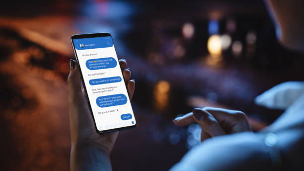 istock Beautiful Woman is Using Smartphone, Chating and Making an Appointment with Friend. Anonymous Female Walking Through Night City Street Full of Neon Light. Over the Shoulder View of a Phone Screen 1338846887