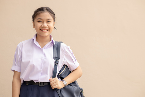 Asian School girl teen cute student in uniform happy smile with bag looking camera with space for text.
