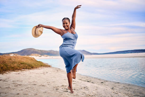 retrato de una joven extasiada disfrutando de su tiempo en la playa - healthy lifestyle women jumping happiness fotografías e imágenes de stock