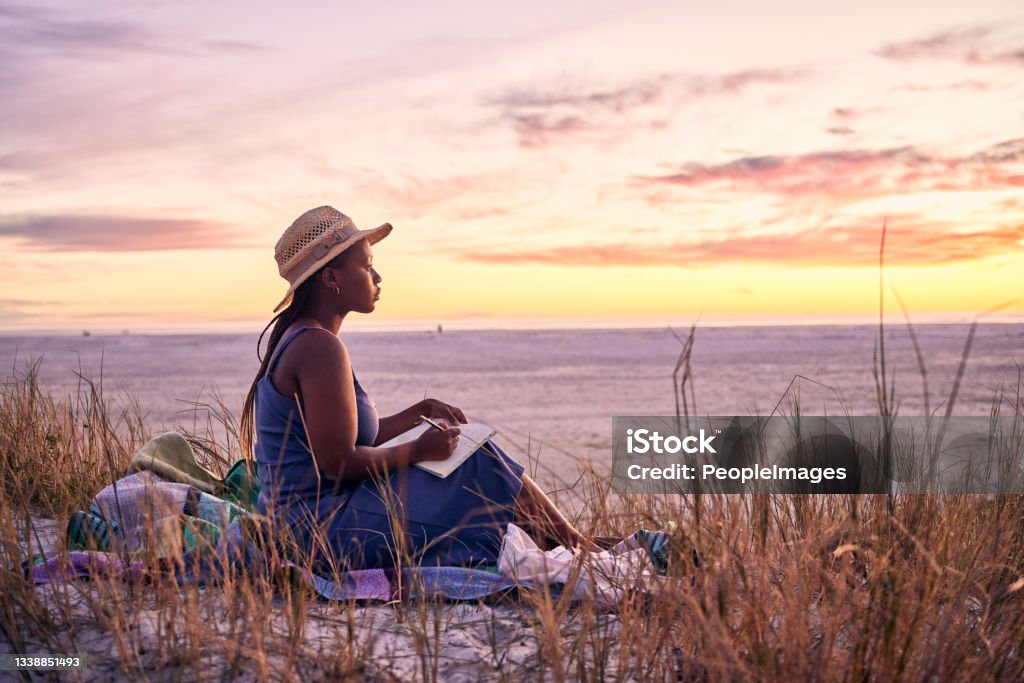 Shot of a young woman writing in her journal at the beach They would have loved the life I made Relaxation Stock Photo