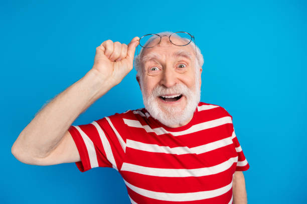 istock Portrait of attractive cheerful friendly grey-haired man touching specs looking at camera isolated over bright blue color background 1338852911