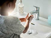 Closeup shot of an unrecognisable boy washing his hands at a tap in a bathroom at home