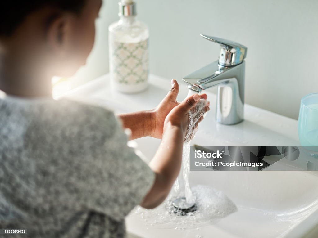 Closeup shot of an unrecognisable boy washing his hands at a tap in a bathroom at home Handwashing is good, because germs are bad! Faucet Stock Photo