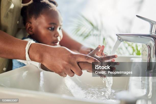 Closeup Shot Of A Mother Helping Her Daughter Wash Her Hands At A Tap In A Bathroom At Home Stock Photo - Download Image Now