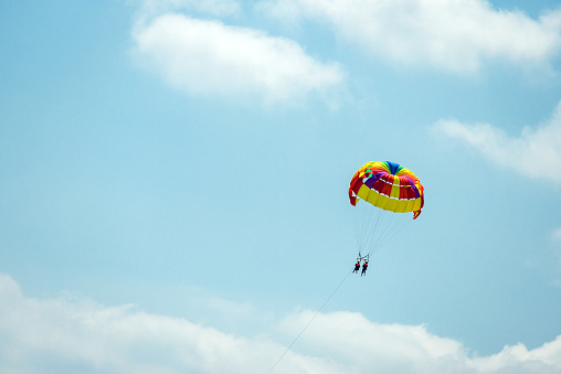 silhouette of happy couple parasailing on tropical sea. Summer extreme actions