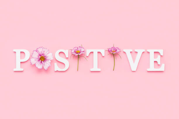 Positive. Motivational quote from white letters and beauty natural flowers on pink background. Creative concept inspirational quote of the day stock photo