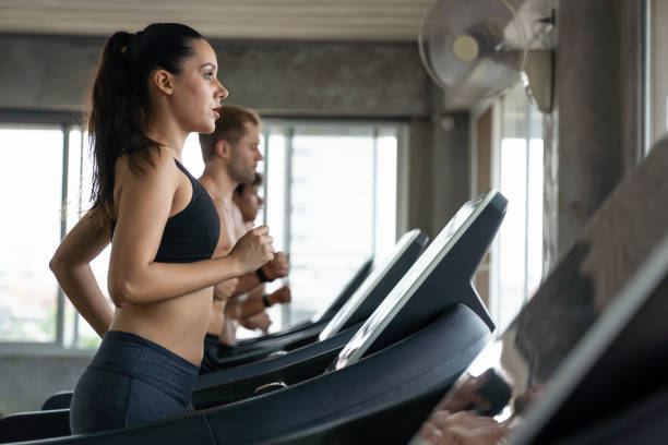 la donna si esercita su cyclette in palestra. gruppo di persone si allena su cyclette in palestra. gruppo di atleti che si allena su cyclette in palestra - spinning health club instructor gym foto e immagini stock