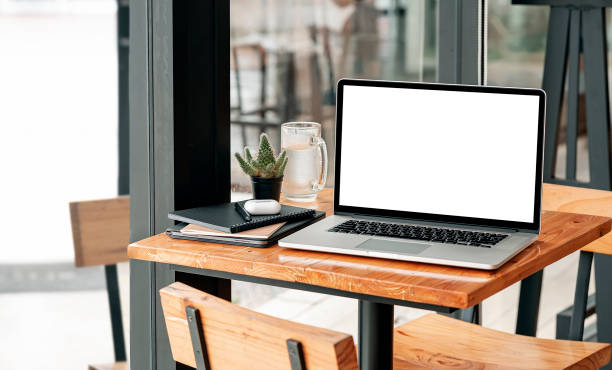 istock Mockup blank screen laptop computer and gadget on wooden table in cafe room. 1338855828
