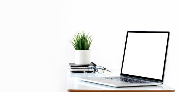 istock Mockup blank white screen laptop computer and houseplant on white top table with copy space. 1338855999
