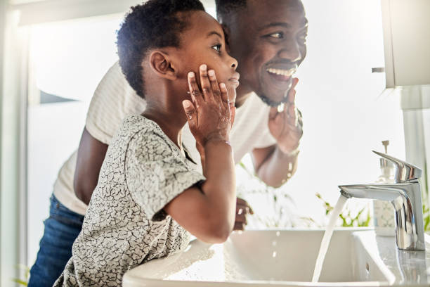 tiro de um pai e seu filho lavando seus rostos juntos em um banheiro em casa - bathroom black faucet - fotografias e filmes do acervo