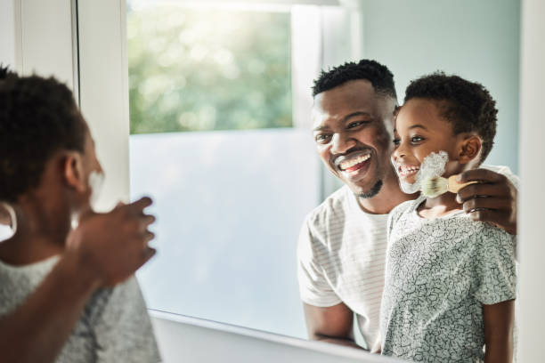 shot of a father applying shaving cream to his son's face in a bathroom at home - shaving men shaving cream mirror imagens e fotografias de stock