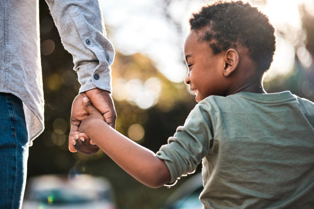 屋外を一緒に歩いている間、父親の手を握っている小さな男の子のリアビューショット - little hands ストックフォトと画像