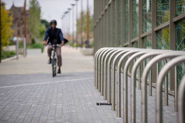 A mature black man wearing formal businesswear and a helmet on a summers day in a city. He is arriving at work on his bicycle after sustainably commuting to work.