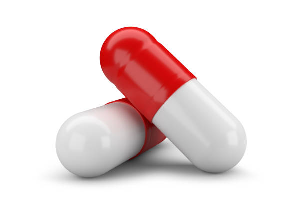 Two red and white capsule pills isolated on white background. stock photo
