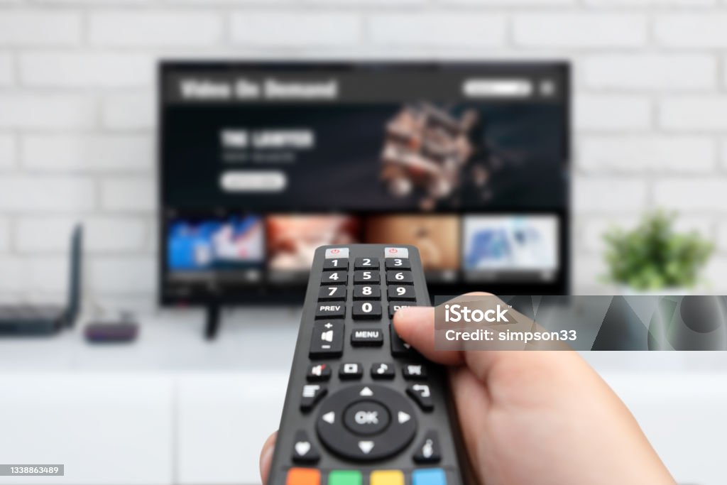 Man watching TV, remote control in hand Man watching TV, remote control in hand. VOD service on TV Television Set Stock Photo