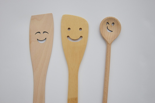 a smile on your face, wooden spatulas on a light background, a happy emotion, we are different, but we are together, concept