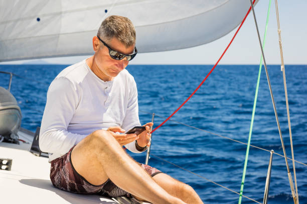istock Businessman with smart phone on sailboat 1338866639