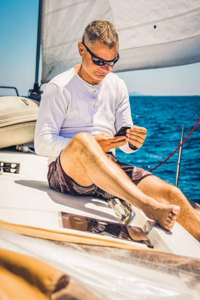istock Businessman with smart phone on sailboat 1338866956