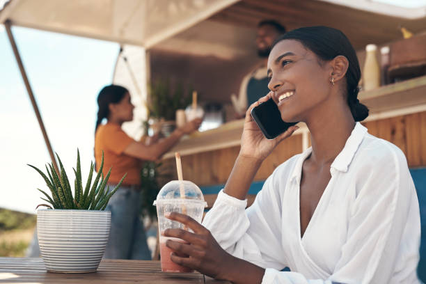 istock Shot of a young woman drinking a smoothie while using her smartphone 1338868523
