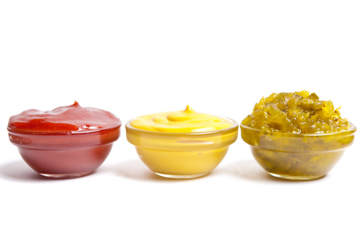 Small bowls of ketchup, mustard and pickle relish.