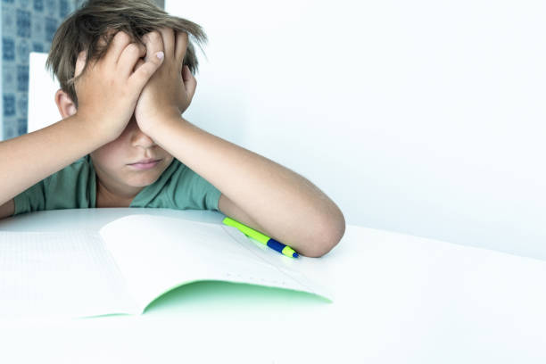 Sad boy with book does school homework. Back to school. Unhappy schoolboy with textbooks. Distance learnin Sad boy with book does school homework. Back to school. Unhappy schoolboy with textbooks. Distance learning tired-student-studying-for-exam-at-library stock pictures, royalty-free photos & images