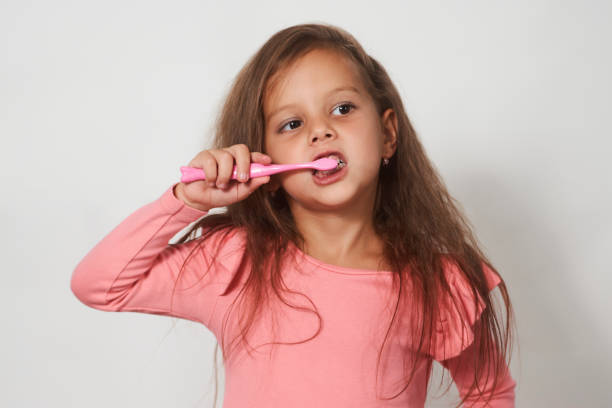 istock Little child girl brushing her teeth on white background. 1338874578