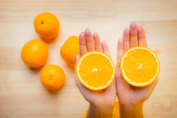 istock Close Up hand holding half orange fruit. 1338877116